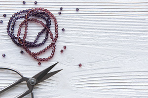 Crafting with beads and scissors on a white wooden surface durin, a Beauty & Fashion Photo by Olena Rudo