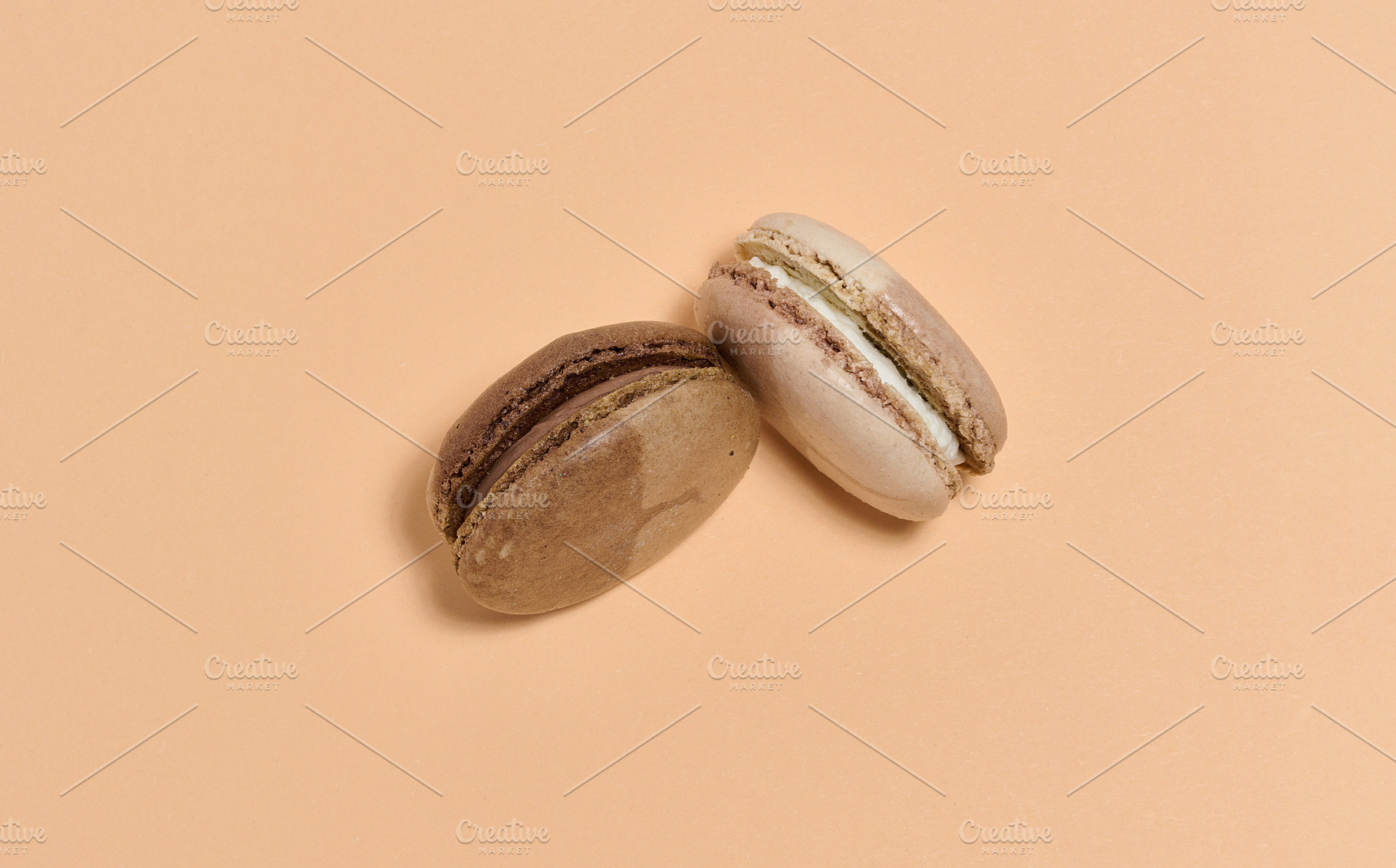 Two brown macarons on beige background, top view, a Food & Drink Photo by ndanko