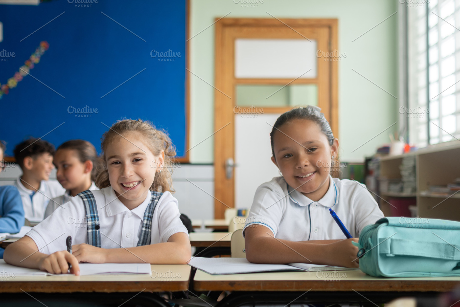 Elementary school girls smiling at the camera during a classroom lesson, a School & Education Photo by etorres69