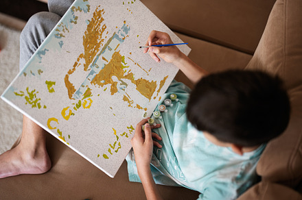 Young male teenager painting picture by numbers on canvas in liv, a Person Photo by AS photostudio