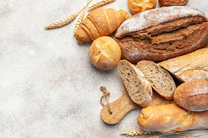 Assorted fresh bakery bread products on textured background, a Food & Drink Photo by Olena Rudo
