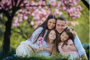 Family sittig on grass in blooming, a Person Photo by HalfPoint
