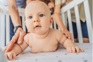 Baby lying on stomach in crib with, a Person Photo by Elizaveta Galitskaya