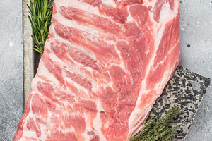 Raw pork spareribs slab on metal tray with herbs and knife flat