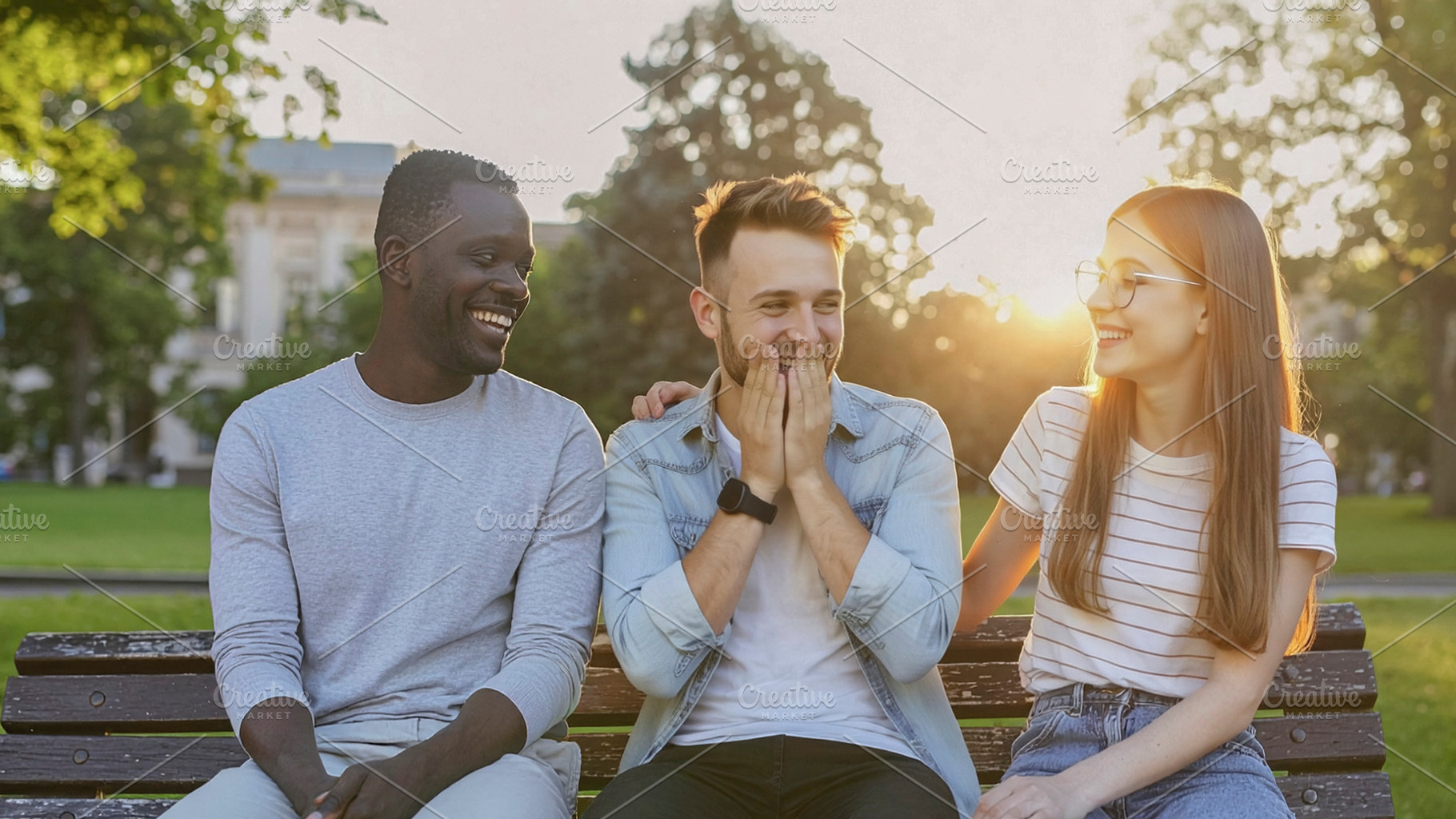 Three friends laughing together on park bench, a Photo by DanFLCreativo