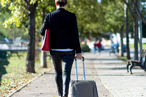 Businesswoman walking with suitcase in park path, a Photo by RF Images