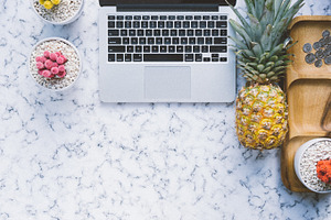Flat lay on marble with pineapple containing flat lay, marble, and laptop