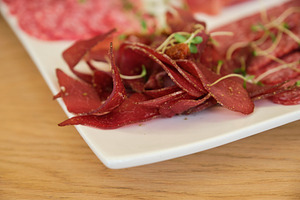 Detailed close-up of thin dried meat slices and spicy salami on white plate., a Food & Drink Photo by Rohan Photography