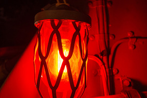 Red alarm light inside an old military submarine with protective, a Transportation Photo by GoodGoods