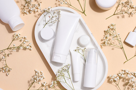 White plastic tubes, jars, and gypsophila branches on a beige ba, a Beauty & Fashion Photo by ndanko