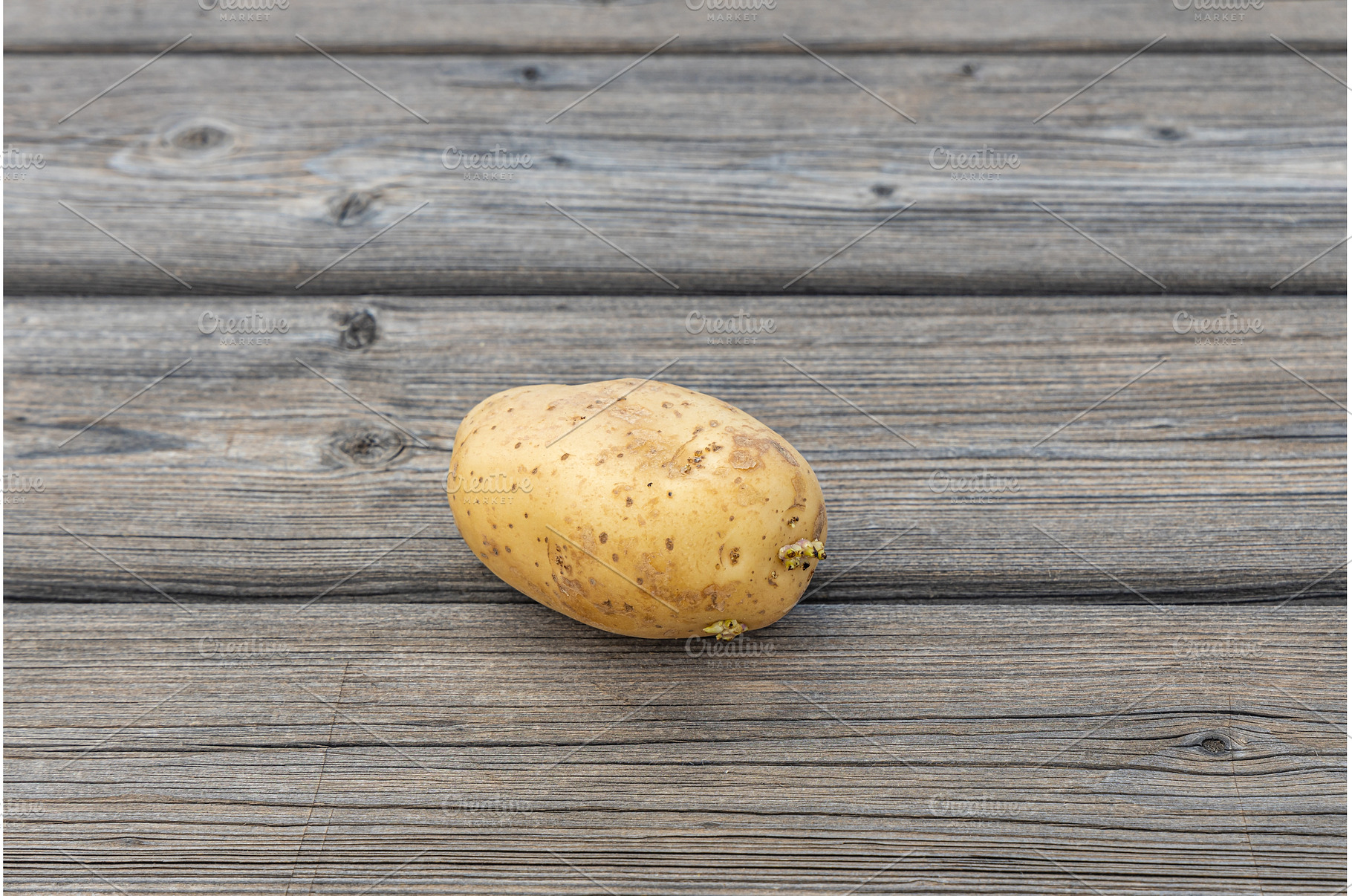 One potato on the gray wooden table, a Food & Drink Photo by Illustrations&photos