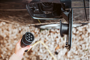 Man charging electric car, hodding, a Transportation Photo by HalfPoint