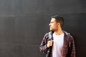 Caucasian man with backpack standing against dark wall, a Person Photo by RF Images