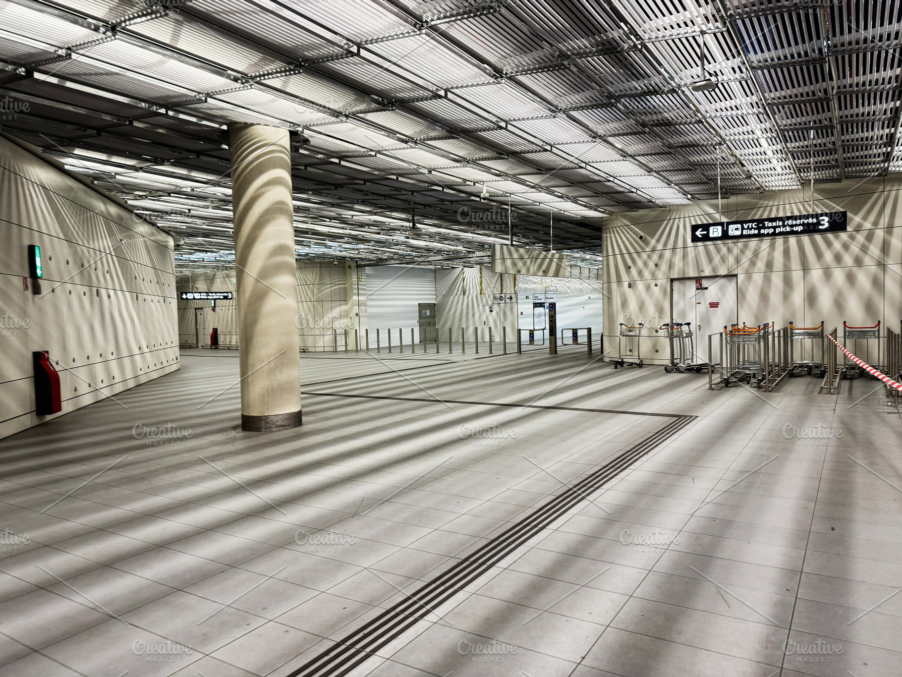 Empty modern airport terminal interior with luggage carts and directional signa, a Photo by AS photostudio