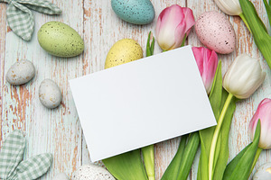Easter eggs and tulips framing a blank card on rustic wooden bac, a Holiday Photo by Olena Rudo