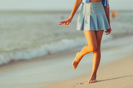 Teen girl's legs on the beach closeup. Girl walking on the beach, a Person Photo by travnikovstudio