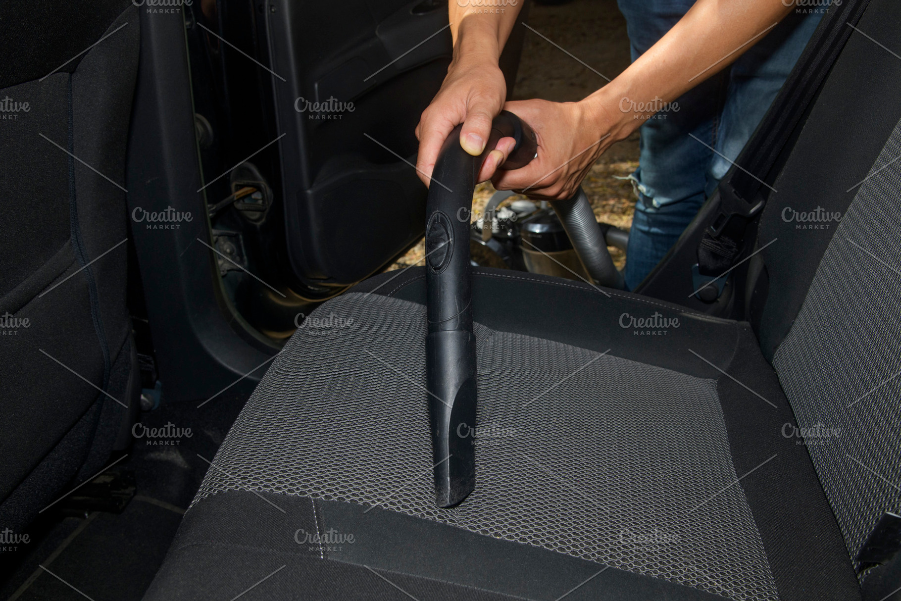 a man vacuums the fabric seat of a car, a Photo by Nito