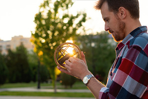 Young man examining vintage globe, a School & Education Photo by Elena Vagengeim