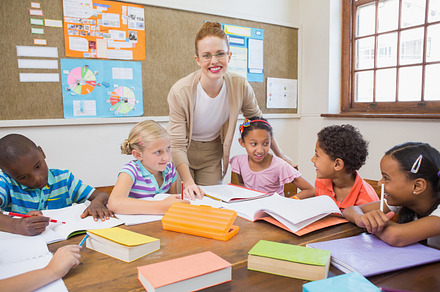 Pretty teacher helping pupils in classroom, a Photo by wavebreak