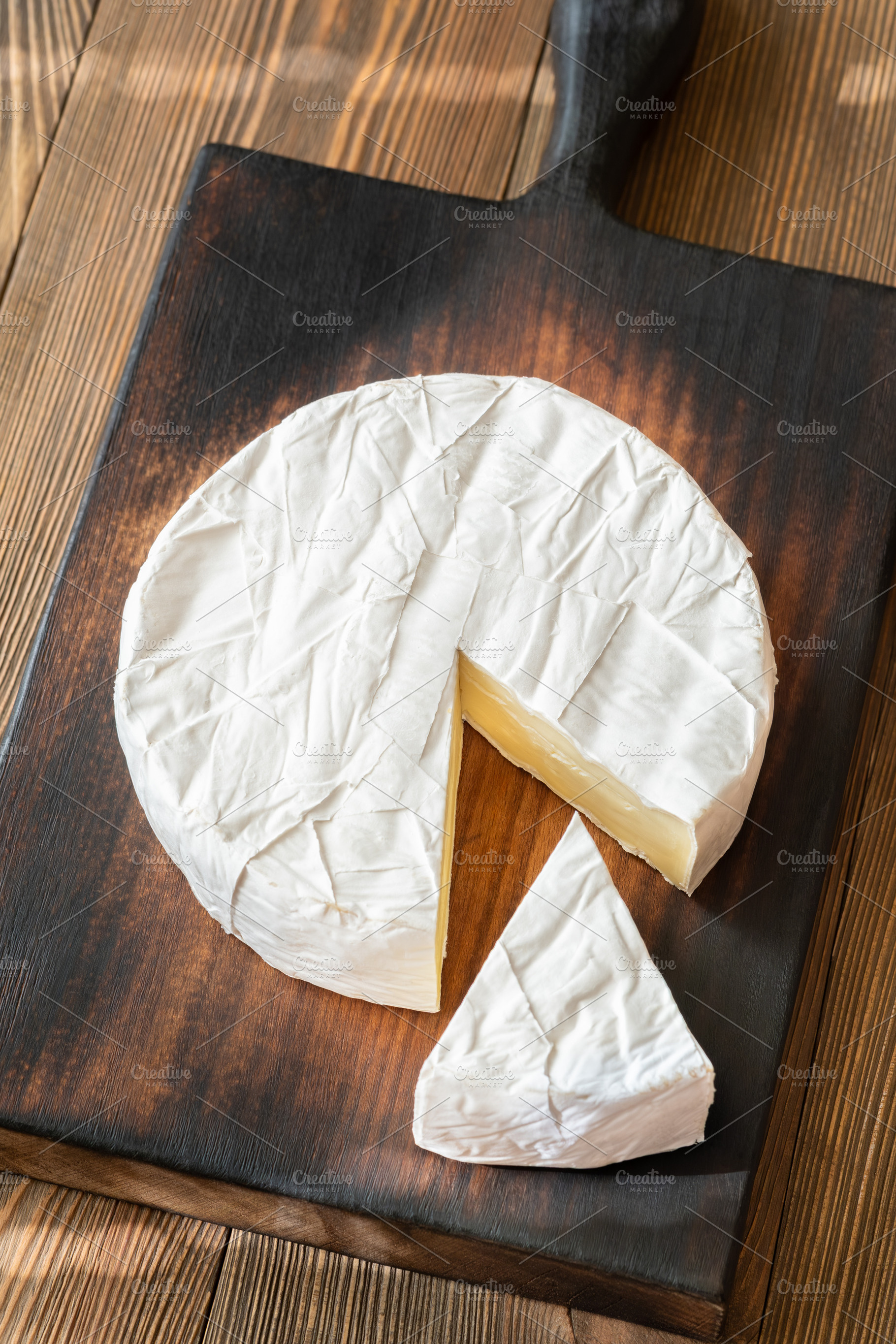 Creamy Camembert Cheese Wheel With Slice Removed On Rustic Woode, a Food & Drink Photo by Alexander Prokopenko