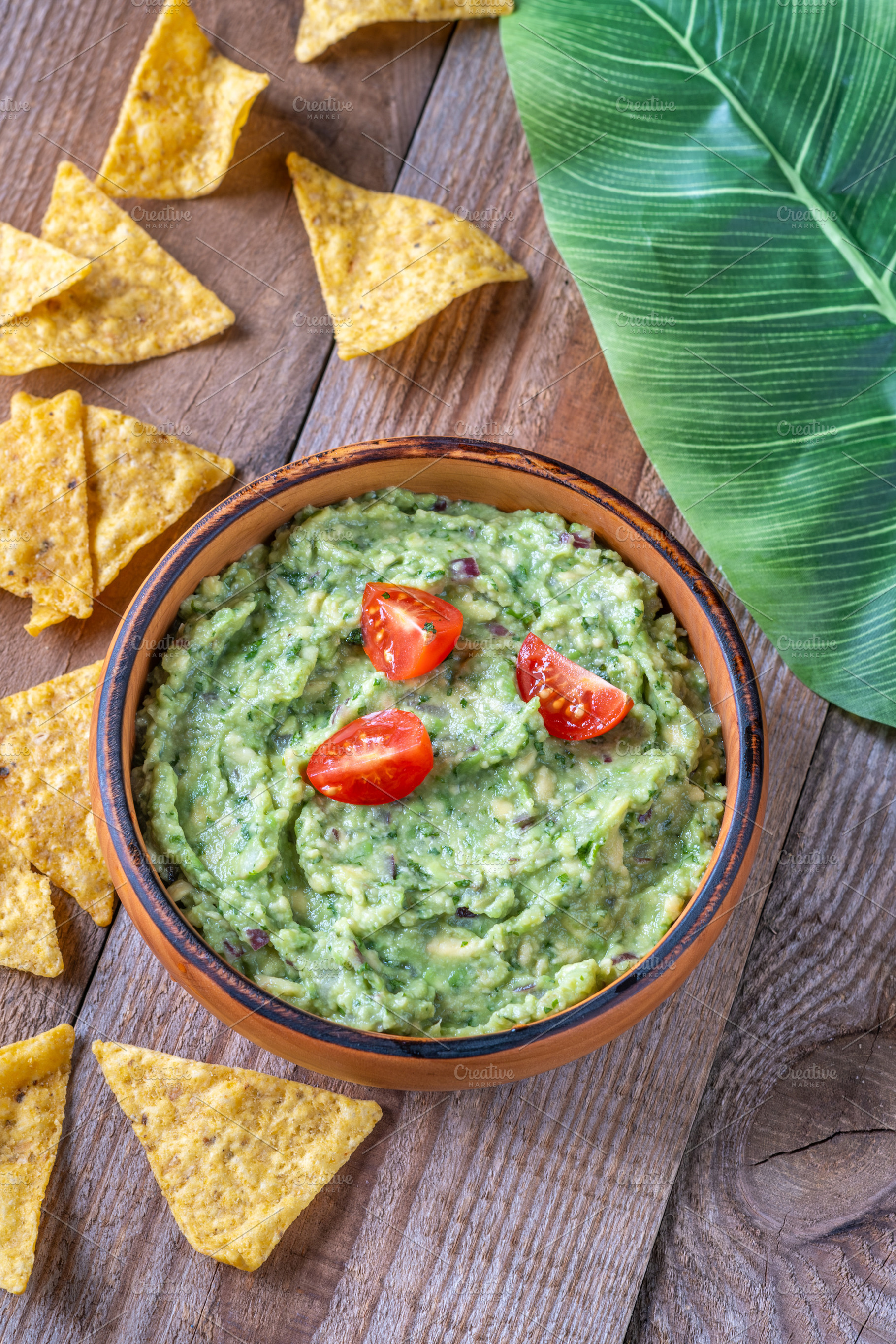 Guacamole with Tortilla Chips on Rustic Wooden Table with Leaf, a Food & Drink Photo by Alexander Prokopenko