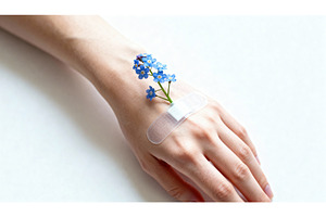 Hand with bandage and blue forget-me, a Health & Medical Photo by tilialucida