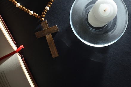 Religious nightstand to pray with Christian cross bible and cand, an Abstract Photo by Davizro's Market