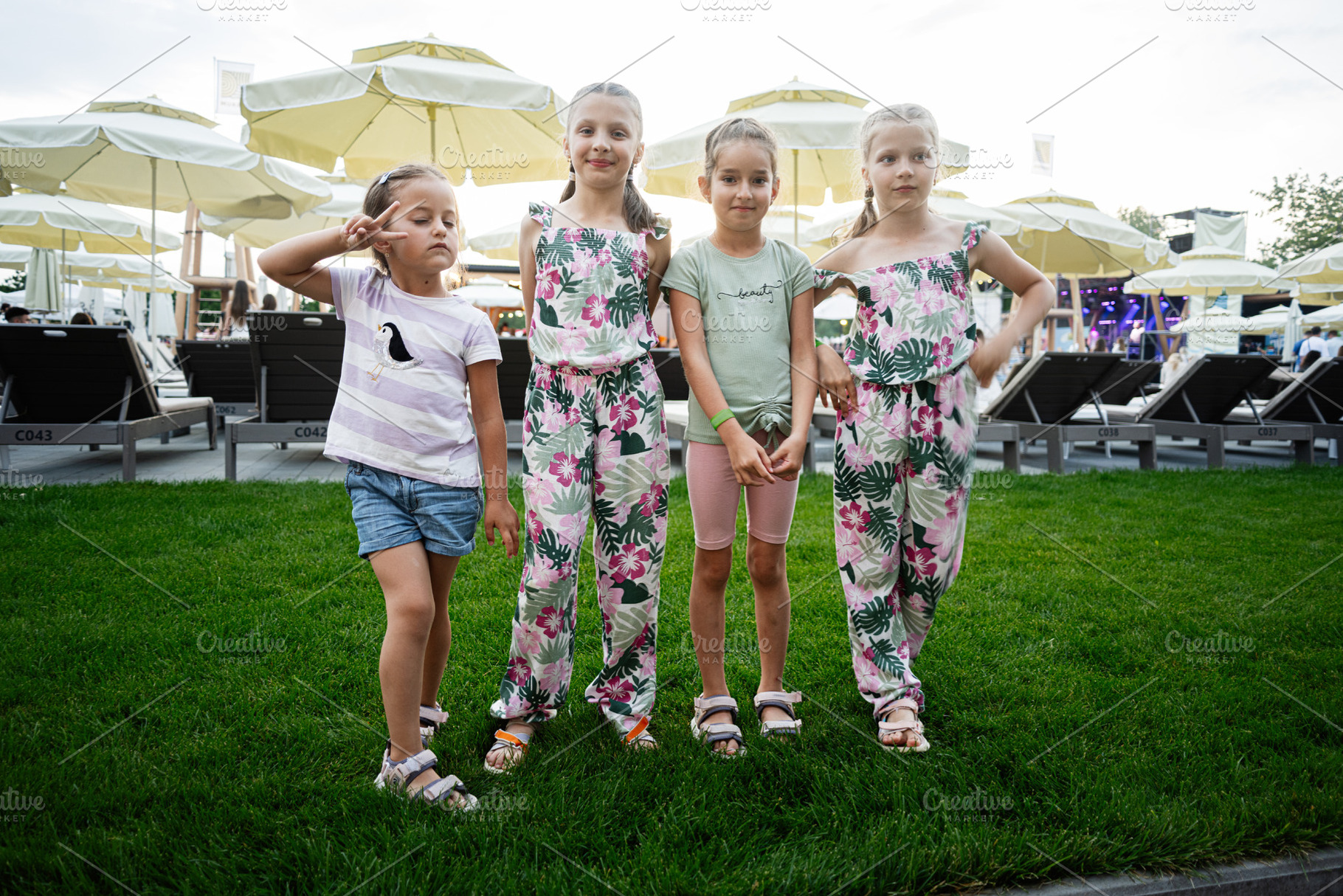 Four young girls posing together on a summer afternoon in a park setting, a Photo by AS photostudio
