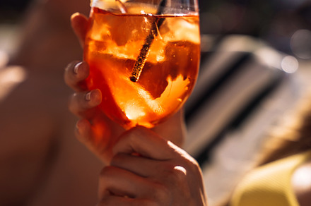 Closeup of young womans hand with neat red manicure holds elegant glass with lo