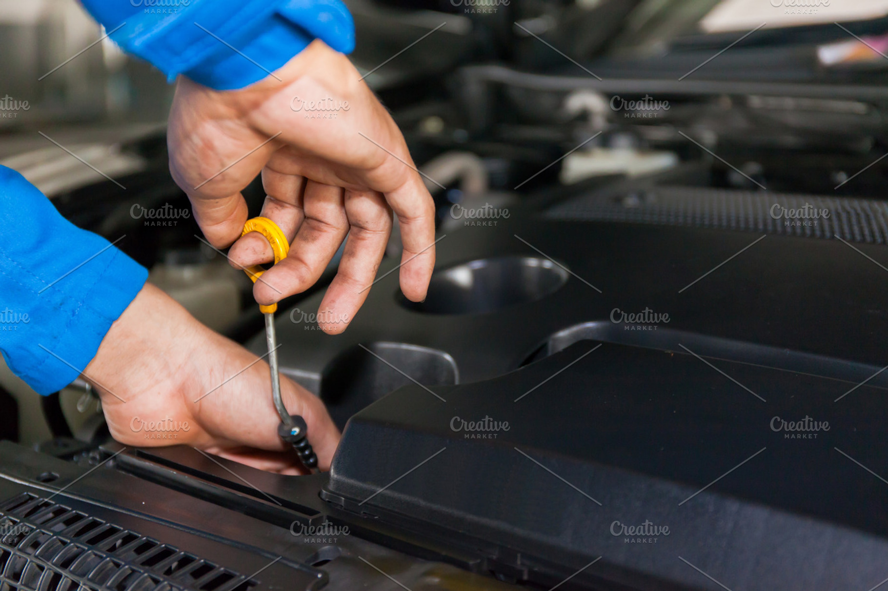 Mechanic checking car's oil level in a car service garage, a Transportation Photo by Twinster Photo