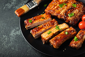 Hot grilled spare ribs from a summer BBQ served on a plate with sauce. Top view