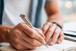 Person writing in notebook with headphones, a Business Photo by AlyaAnd