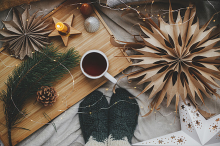 Woman feet in socks on bed with warm cup of tea, christmas stars, a Holiday Photo by Sonjachni