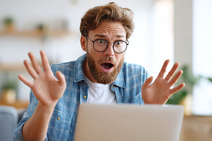Man in blue shirt reacts in surprise while using laptop at home during daytime, a Person Photo by AlyaAnd