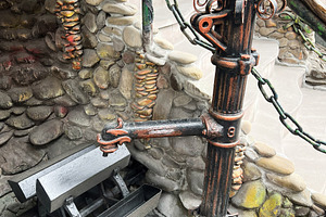 Ornate old pipe and water wheel in a rustic stone setting, a Photo by AS photostudio