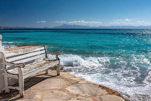 Bench by the sea near a rocky shore, a Photo by Pavel_design