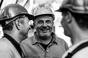 Three male workers share smiles while discussing their day at the construction, an Industrial Photo by AlyaAnd