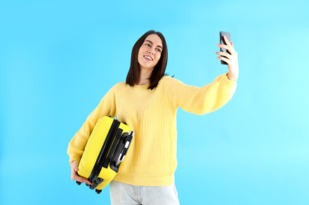 Woman with travel bag doing selfie on blue background, a Person Photo by AtlasStudio PRO