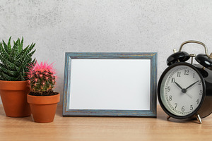 Empty frame, alarm clock and potted plants creating cozy home at, a Business Photo by Olena Rudo