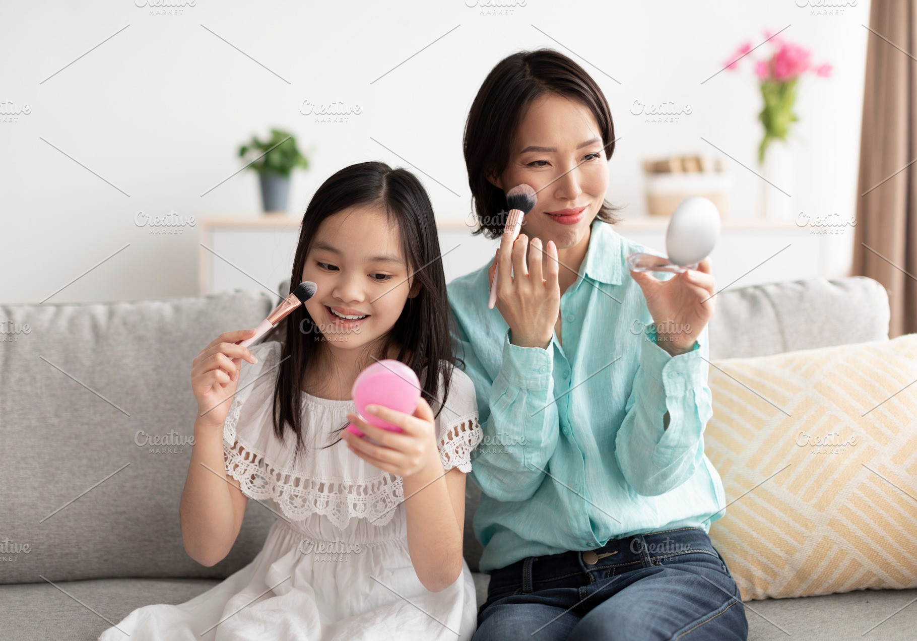 Happy mature Asian woman with her cute little granddaughter applying makeup, ha, a Photo by Prostock-Studio
