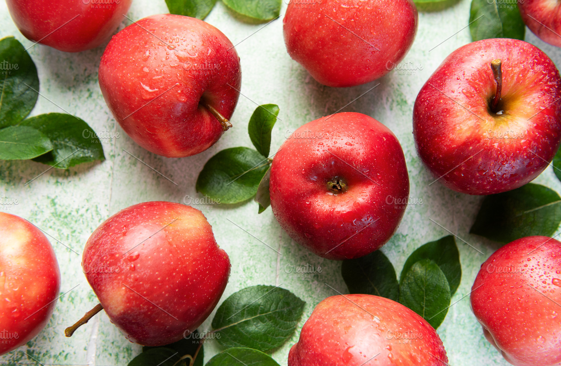 Fresh red apples with green leaves creating appealing pattern on, a Food & Drink Photo by Olena Rudo