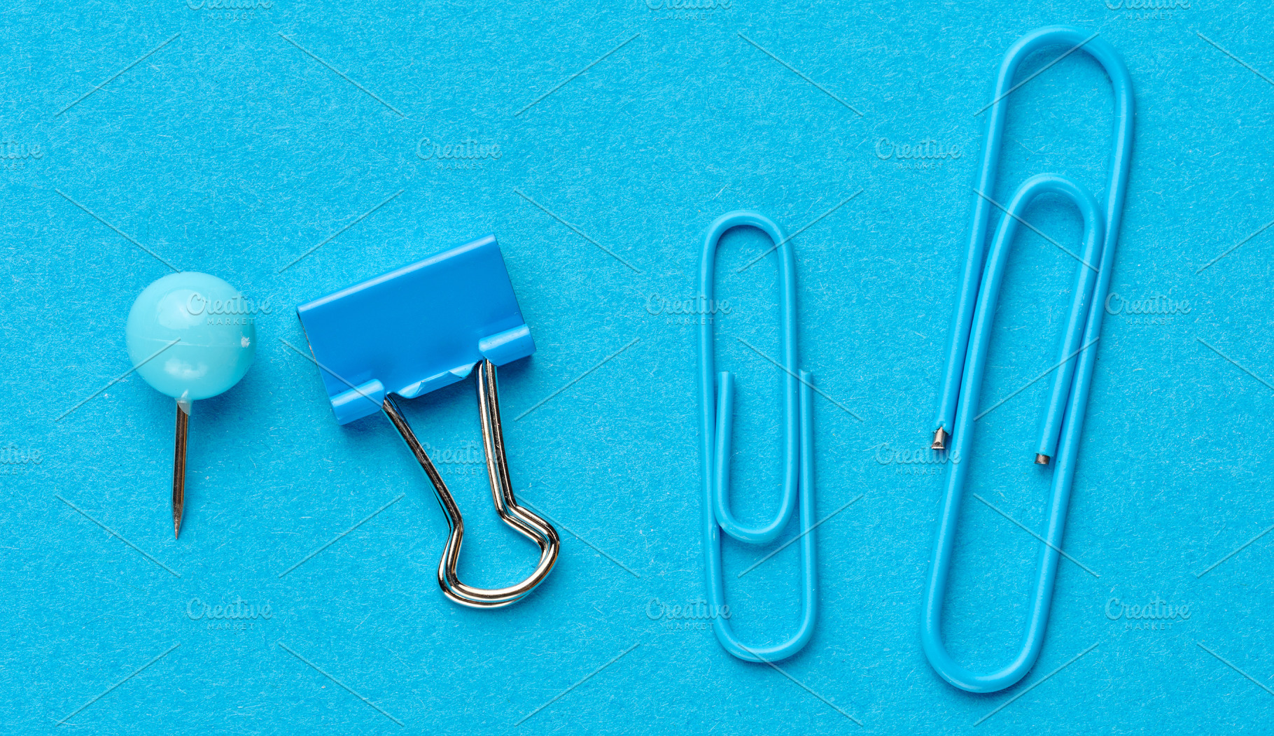 Blue stationery including a pushpin, a binder and two paper clip, a Business Photo by ndanko