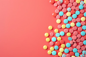Colorful medicine pills with copyspace on pink background, a Photo by AlyaAnd