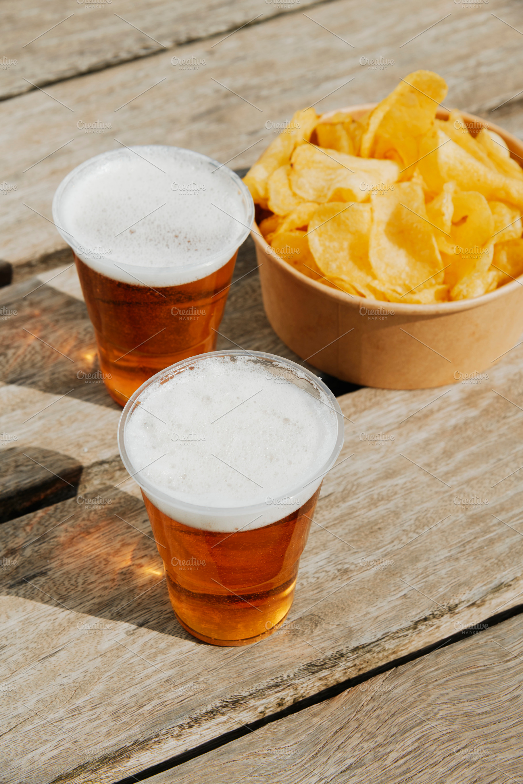 cups with beer and  potato chips on a dock, a Photo by Nito