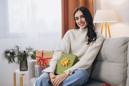 Beautiful happy woman unwrapping New Year or Christmas presents