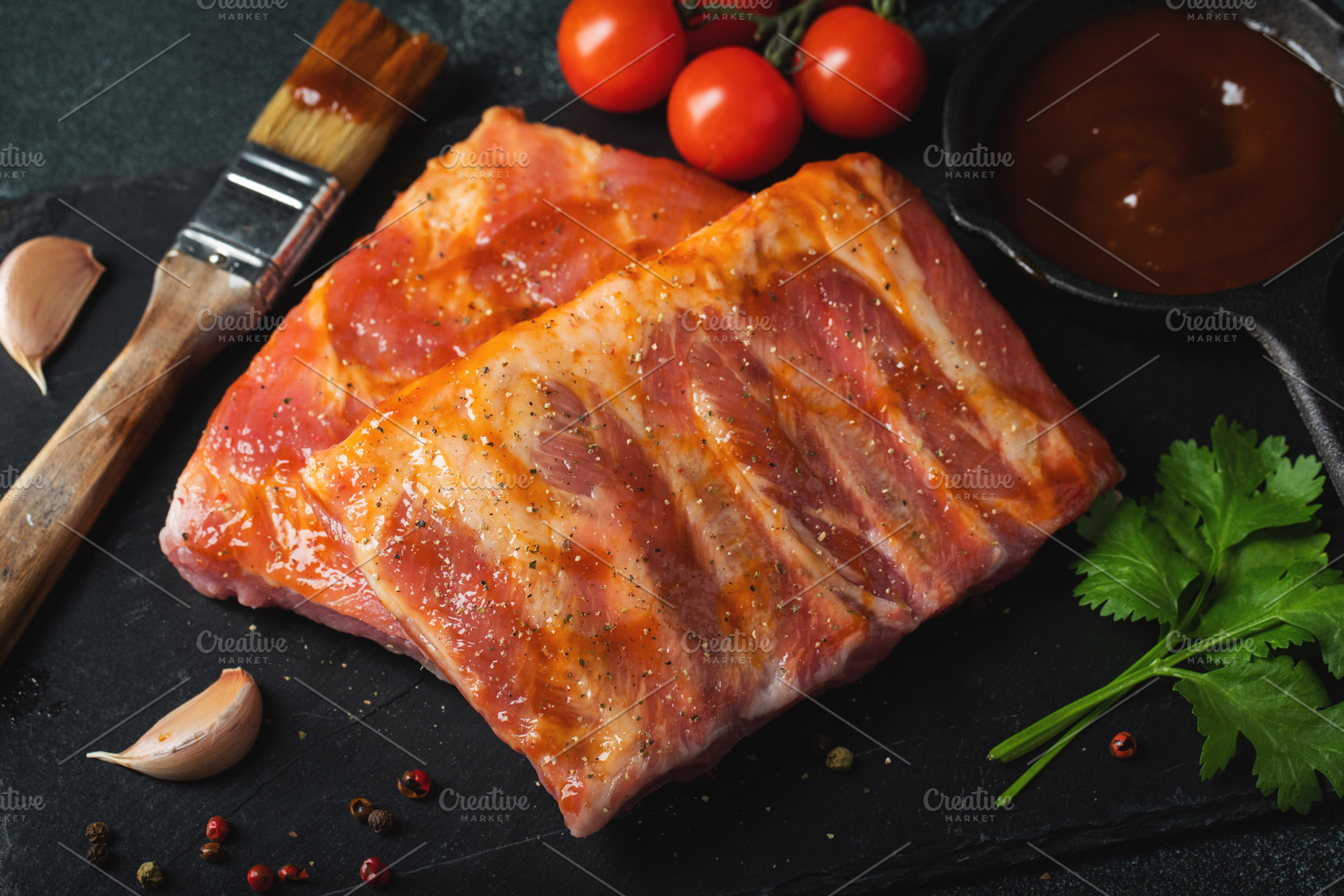 Ready for BBQ raw pork spare ribs with barbecue sauce. Black background. Top vi, a Food & Drink Photo by Budarinphoto