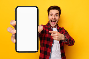 Shocked guy pointing at white empty smartphone screen