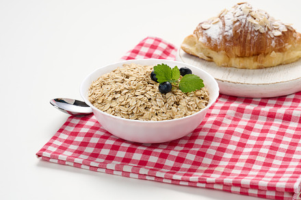 Raw oatmeal in white ceramic plate and croissant on white table,, a Food & Drink Photo by ndanko