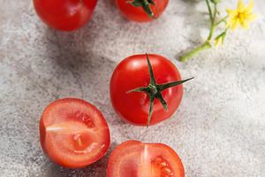Fresh red cherry tomatoes on concrete background with leaves, a Food & Drink Photo by Olena Rudo