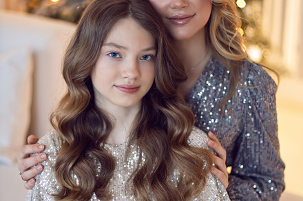 Mother and daughter in beautiful light dresses are standing at the Christmas tr, a Holiday Photo by SaulichPhoto